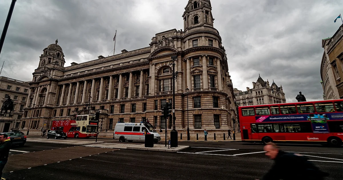 Police vehicles and traffic passing a government building in central London.